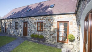 A stone house with a sloped roof, multiple windows, and a well-maintained lawn.