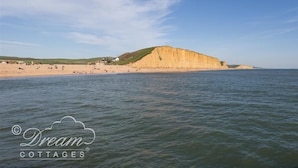 Eine Küstenlandschaft mit einem Sandstrand und einer markanten Klippe.