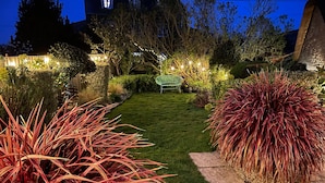 Ein gepflegter Garten mit Rasen, verschiedenen Pflanzen und einem grünen Stuhl.