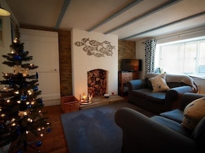 A cozy living room with a fireplace, a Christmas tree, and a sofa.