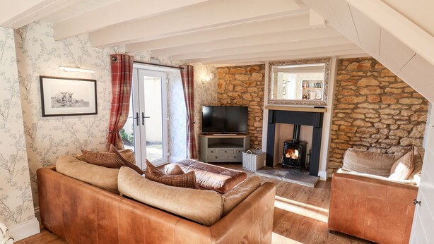 A cozy living room with a stone fireplace, leather sofas, and a television. - The Pheasantry (Scarborough)