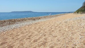 Une plage de galets offrant une vue dégagée sur la mer et le lointain rivage.