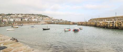 A harbor with boats, a stone wall, and a town in the background.