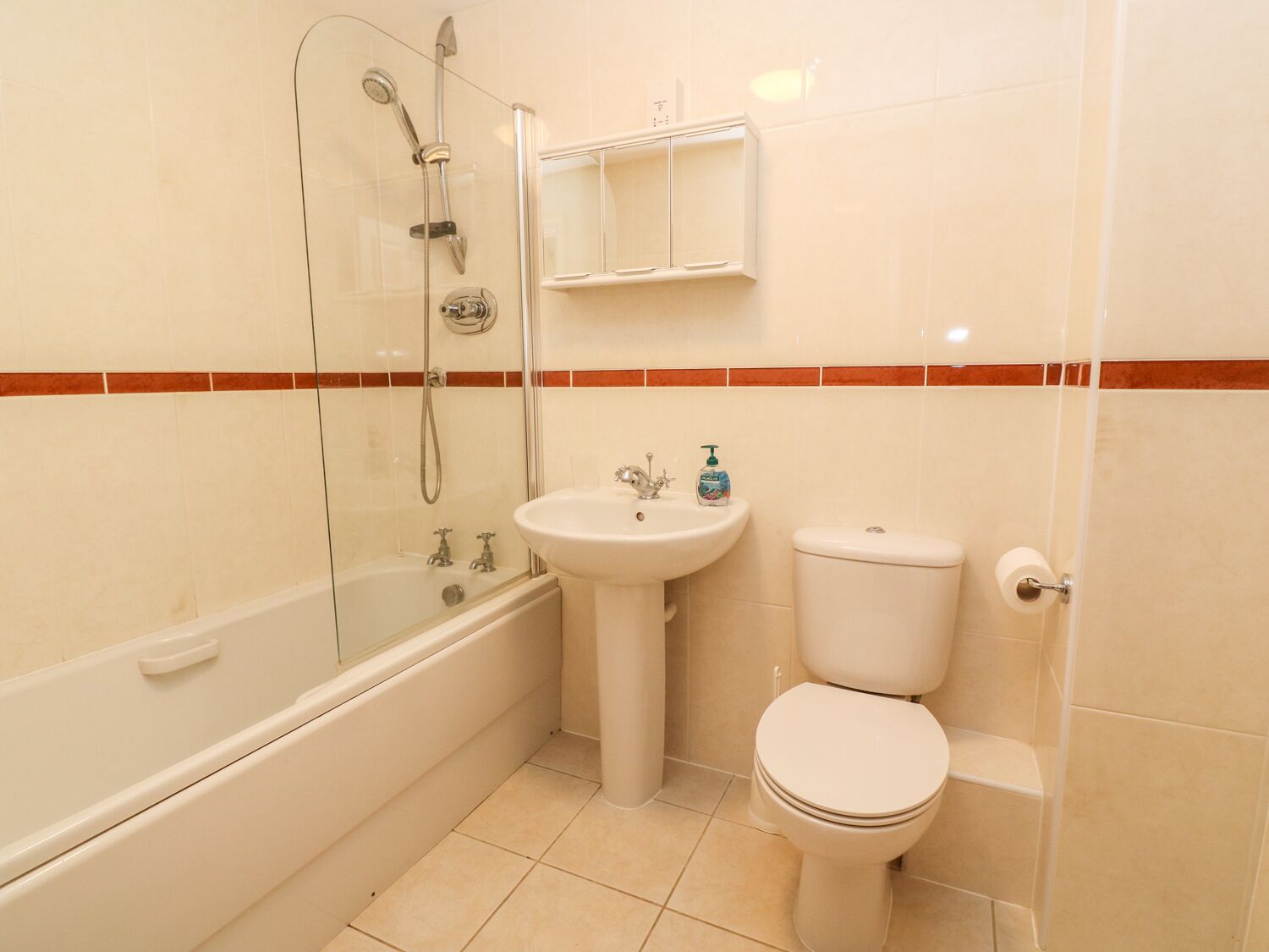 Un baño con ducha de vidrio, lavamanos y retrete.
