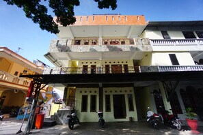 A multi-story building with a balcony on the second floor, a covered entrance, and several parked motorcycles.