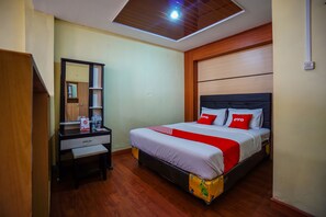A hotel room with a bed, a desk, a mirror, and a wardrobe. - OYO 1912 Kengkang Residence (Manado)