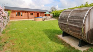 A wooden cabin with a hot tub and a barrel in the yard. - Yew Lodge (Oakham)