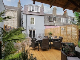 A patio area with a wooden deck, wicker furniture, and potted plants.