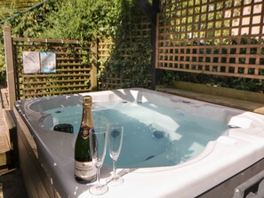 A hot tub with a bottle of champagne and two glasses.
