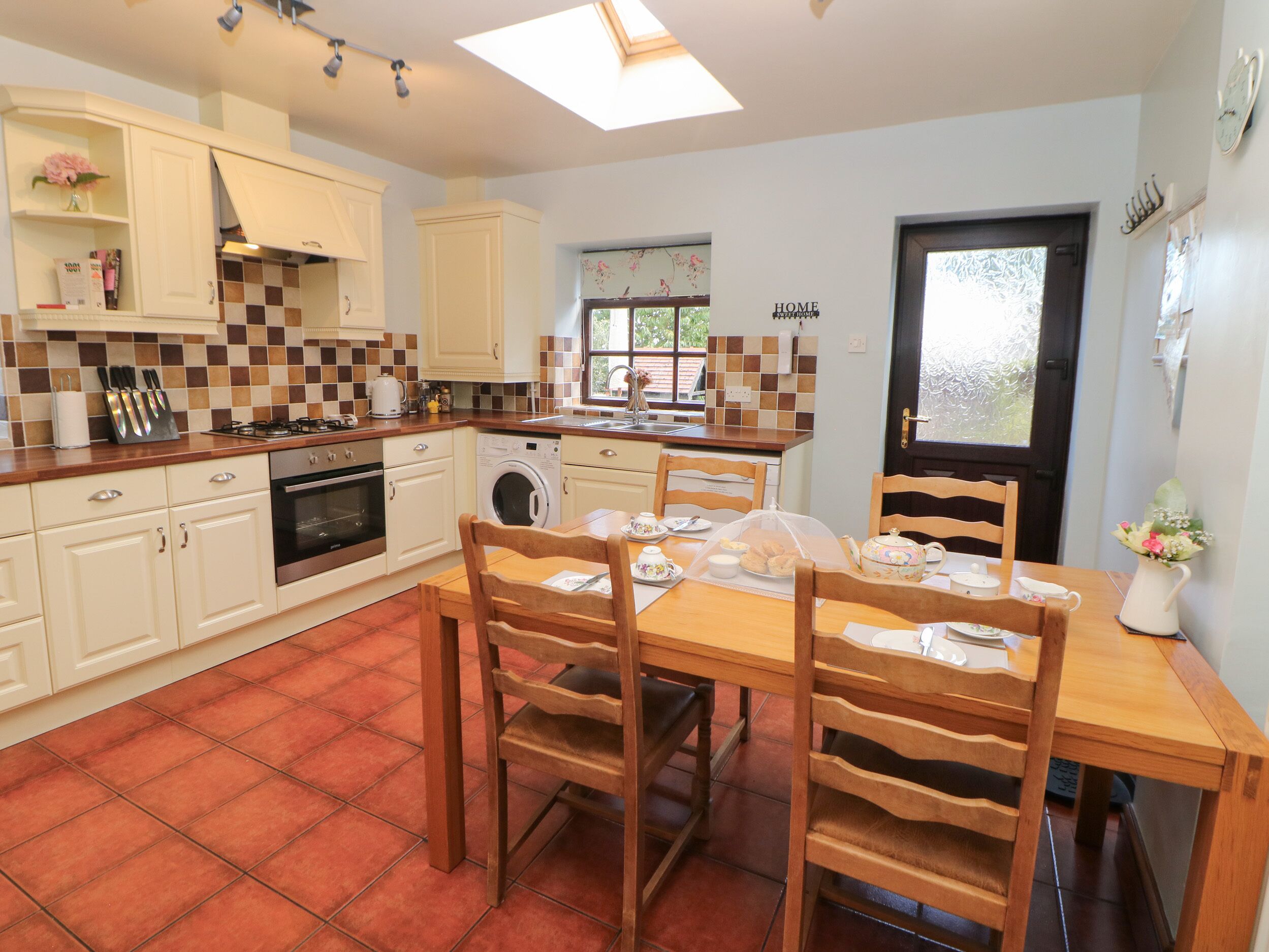 A compact kitchen with a dining area, featuring a sink, stove, oven, and washing machine.