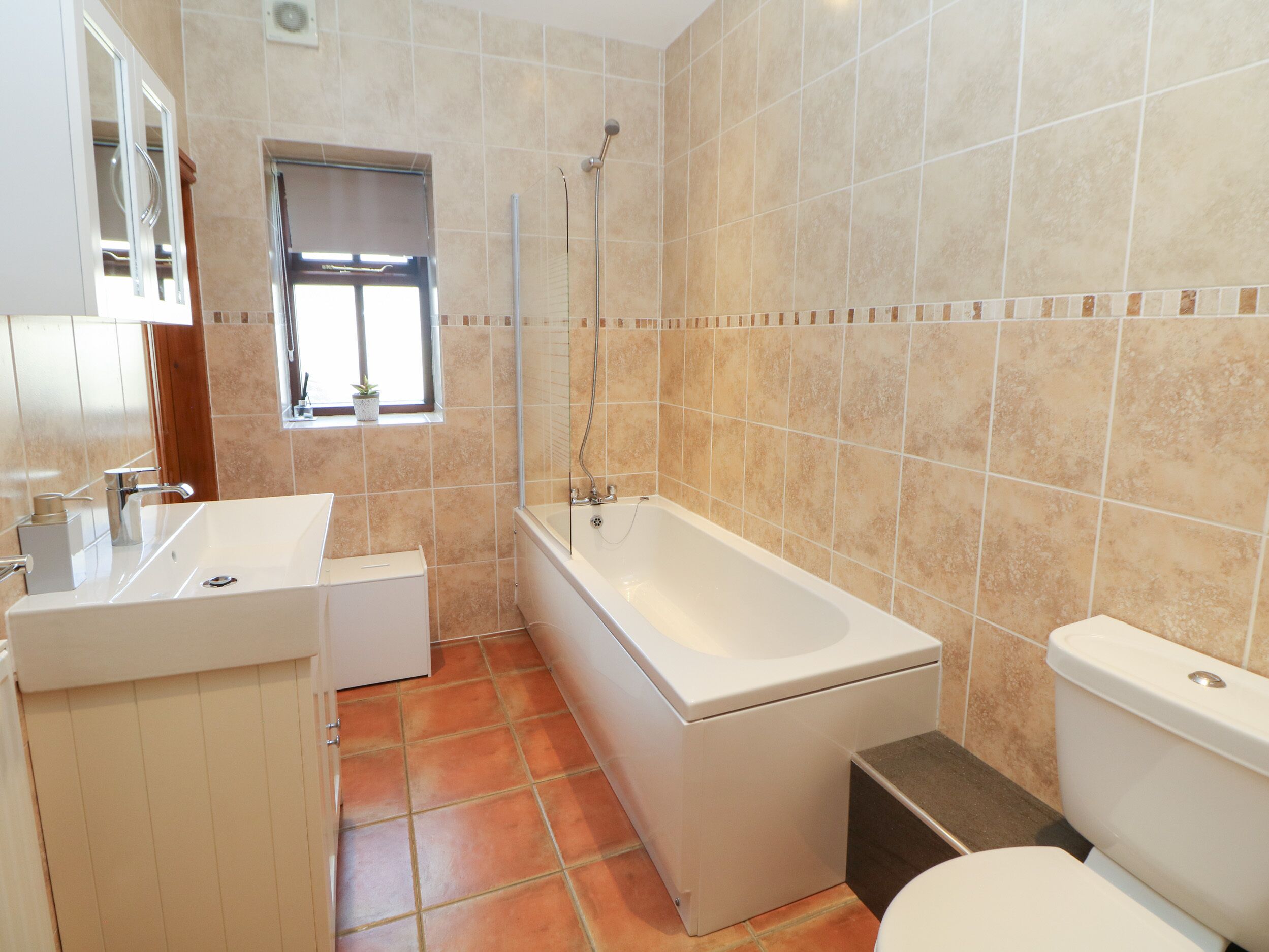A bathroom with a bathtub, toilet, sink, and a window.