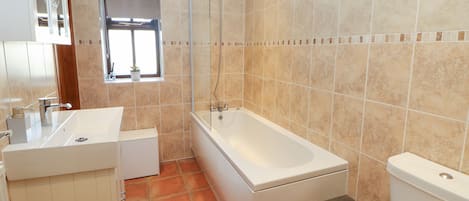A bathroom with a bathtub, toilet, sink, and a window.