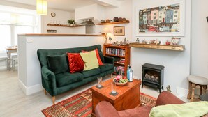 A cozy living room with a green sofa, a wooden coffee table, and a bookshelf. - Harbour Catch Cottage (Weymouth)