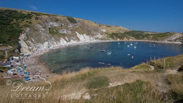 Une zone côtière avec une plage, des bateaux et un ciel dégagé.