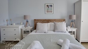 Une chambre à coucher comprenant un lit, deux tables de chevet, une commode, une armoire et un tableau encadré accroché au mur.