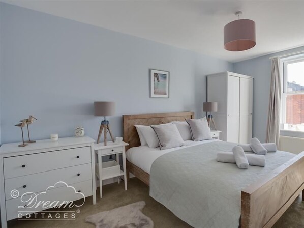 Un dormitorio con cama, mesitas de noche, un armario y una ventana.
