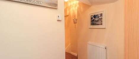 A narrow hallway with a radiator, a framed picture, and a wall-mounted light fixture.