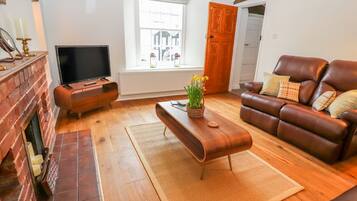 Un salon avec une cheminée, un téléviseur, un canapé en cuir marron et une table basse en bois.
