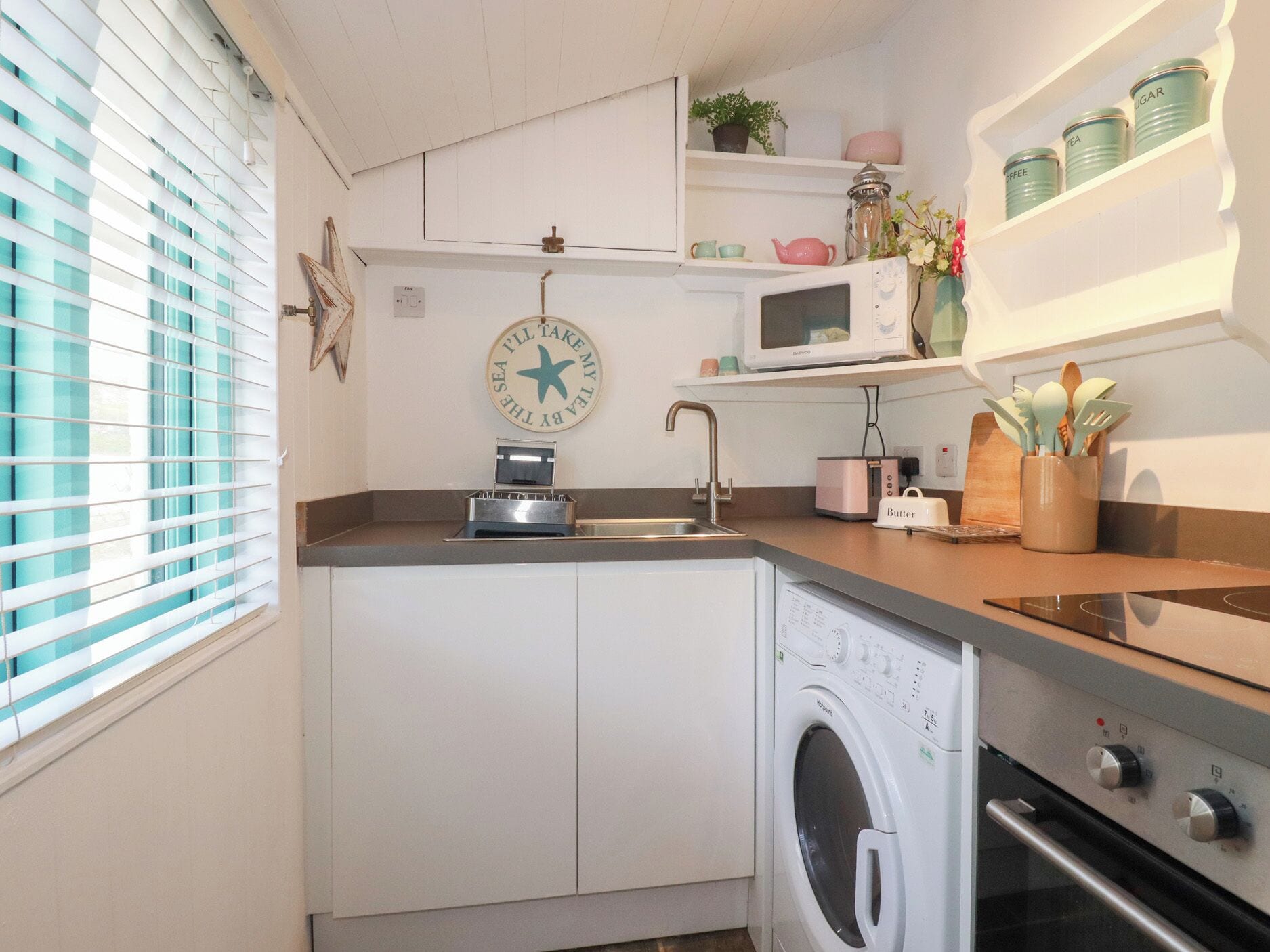 A compact kitchen with a washing machine, a microwave, and a toaster.
