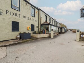 A building named 'Port William' with a signboard, windows, and outdoor seating area. - Smugglers Cottage (Tintagel)