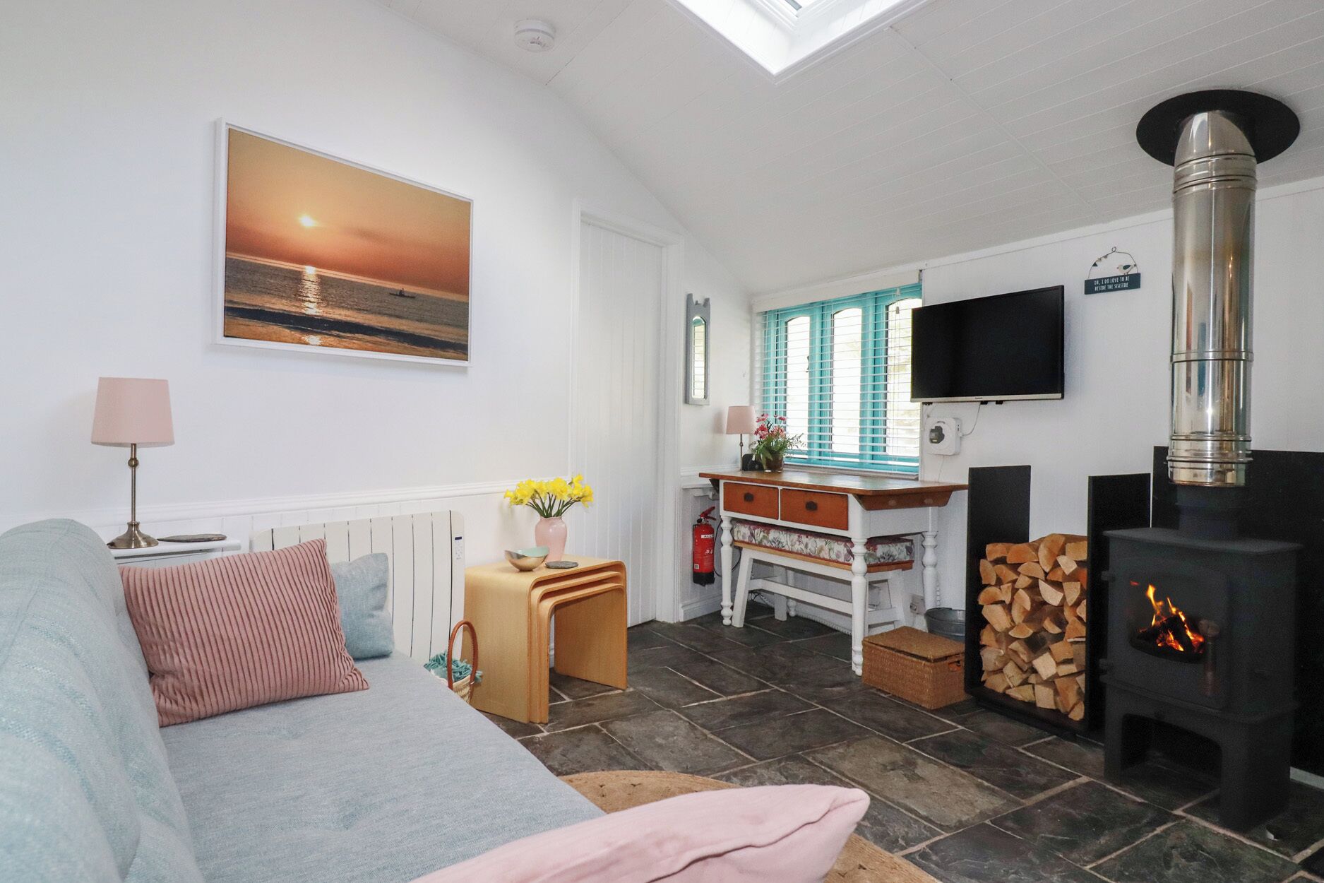 Una sala de estar acogedora con un sofá, una mesa, un televisor, una chimenea y un cuadro en la pared.