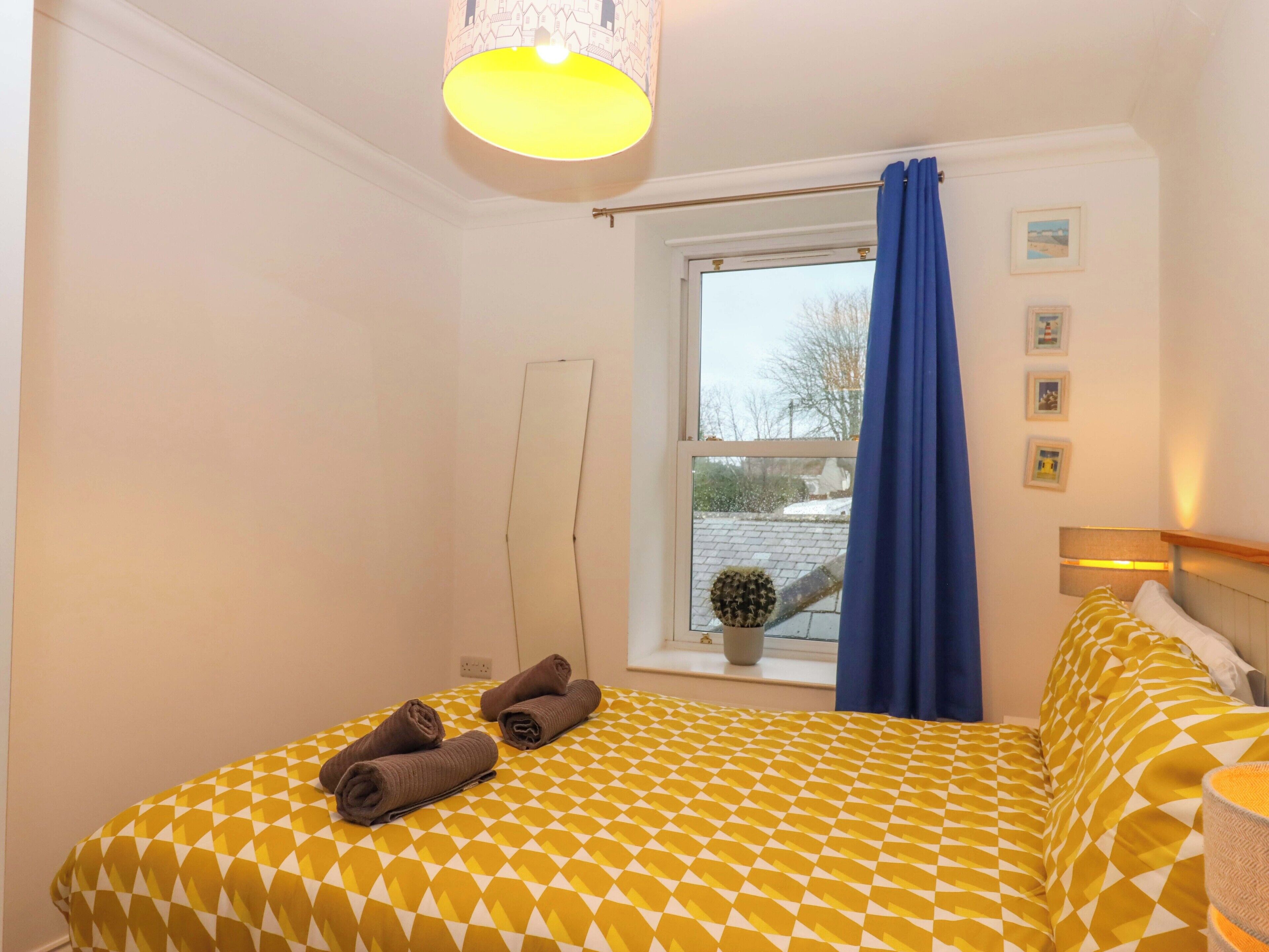 A hotel room with a bed, a window with a view of the outside, a potted plant, and a lamp.