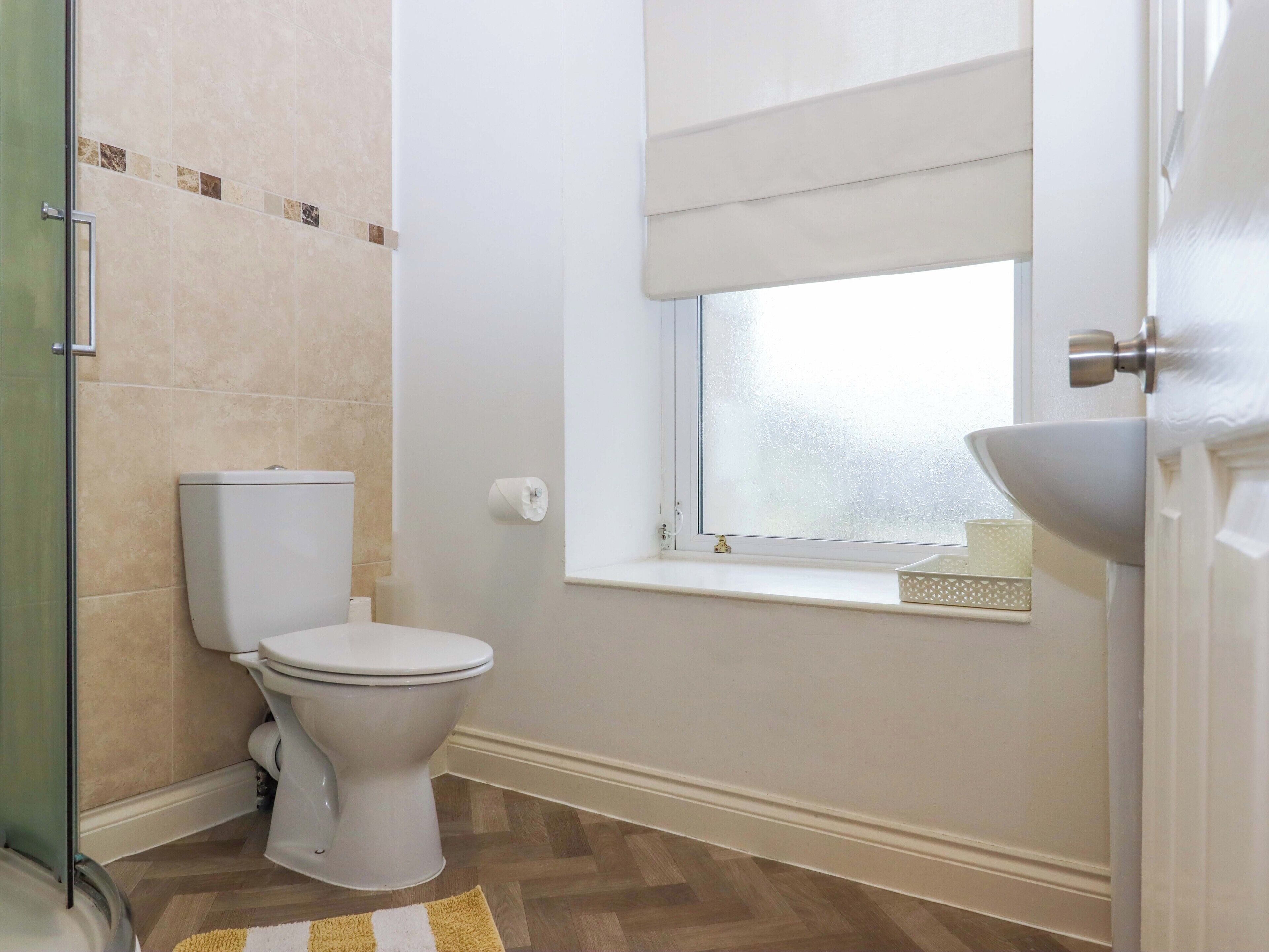 Un bagno con il water, una finestra e un lavandino.