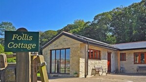 Une petite maison en pierre avec une pancarte indiquant « Follis Cottage ».