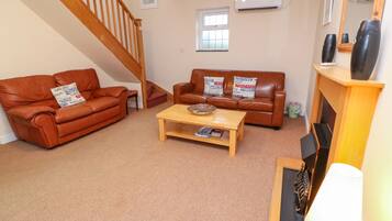 A living room with a brown leather sofa, a wooden coffee table, and a staircase.