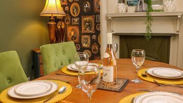 A dining table set with plates, cutlery, and wine glasses, surrounded by green upholstered chairs.