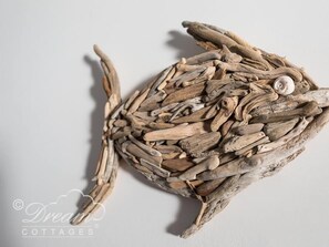 Un objet décoratif composé de morceaux de bois flotté disposés en forme de cercle, agrémenté d’un coquillage.
