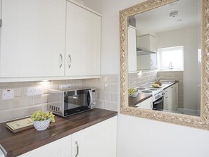 A modern kitchen with white cabinets, a microwave, and a sink.