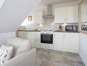 A compact kitchen with white cabinets, a stove, an oven, and a microwave.