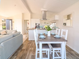 Una cocina moderna con armarios blancos, una isla central con asientos y una mesa de comedor preparada para seis comensales.