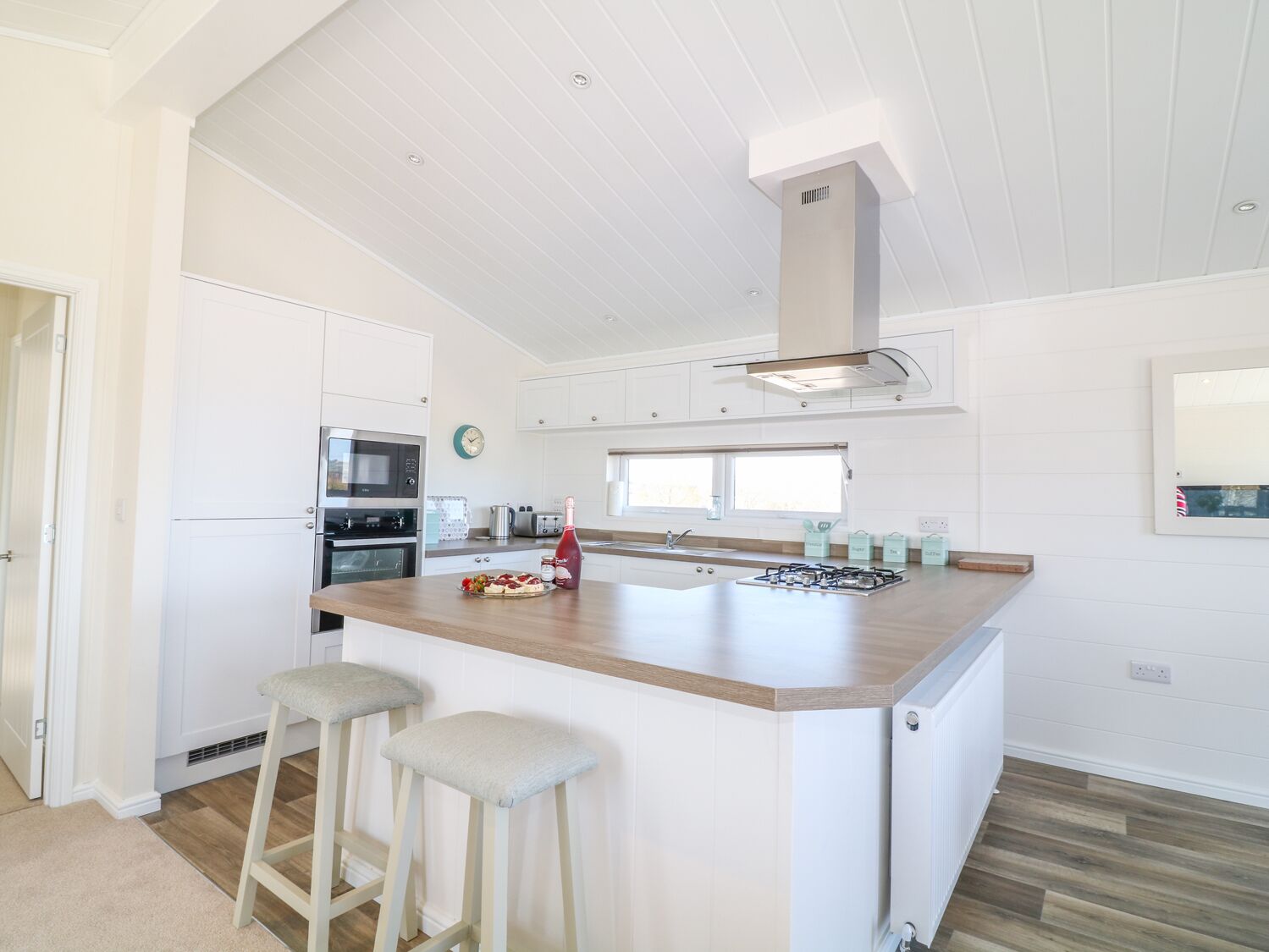 A modern kitchen with white cabinetry, a central island with stools, a microwave, oven, and a gas stove.