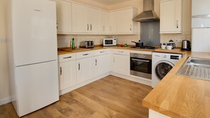Eine moderne Küche mit weißen Schränken, einem Bosch-Kühlschrank, einer Mikrowelle, einem Toaster, einer Spüle und einer Waschmaschine.