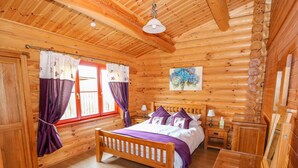 A wooden cabin bedroom with a bed, nightstands, and a painting on the wall.
