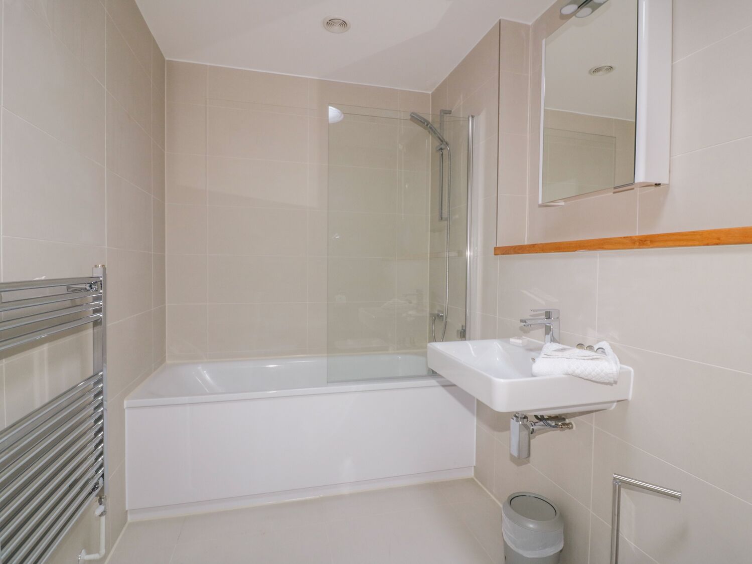 Une salle de bain moderne avec une douche à parois de verre, une baignoire blanche et un lavabo surmonté d’un miroir.