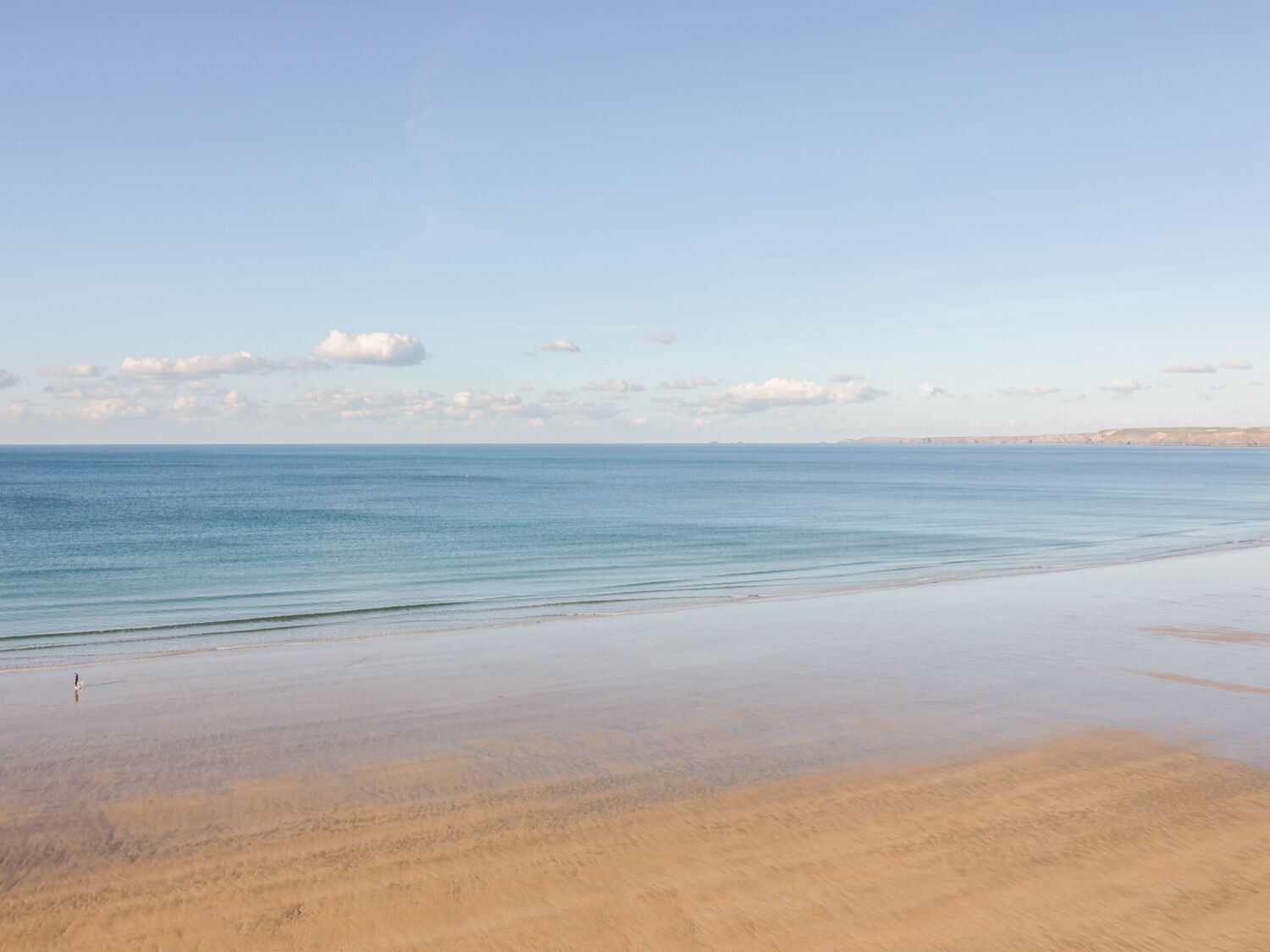 Een strand met een breed zandstrand en rustig water.