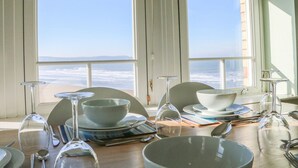 A dining area with a table set for four, overlooking a beach. - Hartland View (Woolacombe)