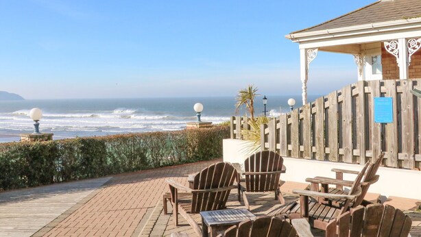 A patio with wooden chairs and tables overlooking the ocean. - Hartland View (Woolacombe)