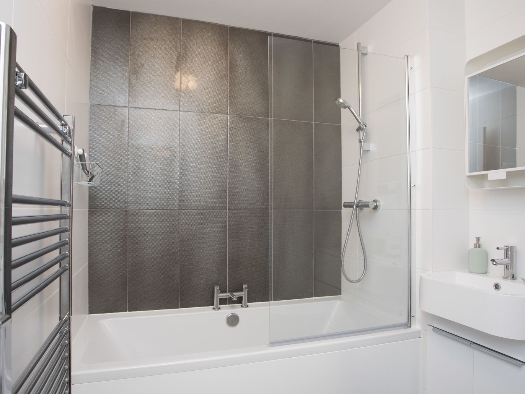 A modern bathroom with a glass-enclosed shower, a white bathtub, and a white sink with a mirror above it.