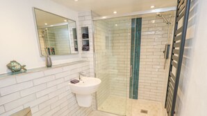 Une salle de bain moderne avec une douche à parois de verre, un lavabo blanc et un grand miroir.