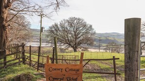 A wooden sign with 'Conwy Cottage' and 'Cymru Uchaf' written on it, indicating a location. - Cymryd Uchaf (Conwy)