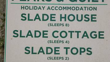 Segnaletica per Peaks & Quiet Holiday Accommodation che elenca Slade House, Slade Cottage e Slade Tops, con rispettivamente capacità di ospitare 8, 4 e 2 persone.