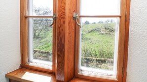 Una ventana de madera con vistas a un paisaje verde.