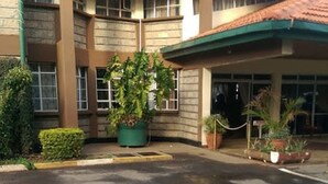 A building with a sign reading "GARDEN" and a covered entrance area with potted plants. - Garden Hotel (Machakos)