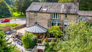 Une maison en pierre avec un grand jardin, un belvédère et un panneau solaire sur le toit.
