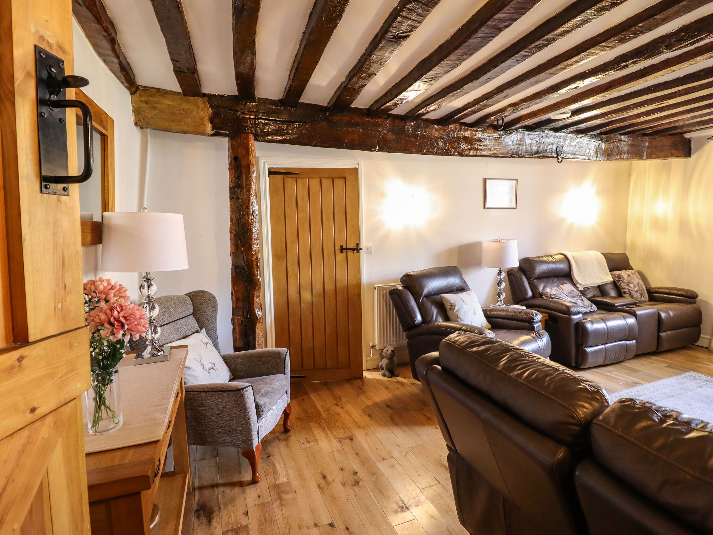 Una sala de estar acogedora con pisos de madera, chimenea, sofás de cuero y puerta de madera.