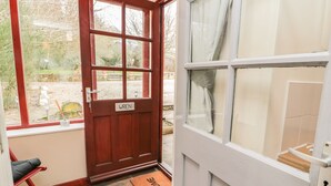 Una puerta de madera con una placa, una silla roja y un felpudo.